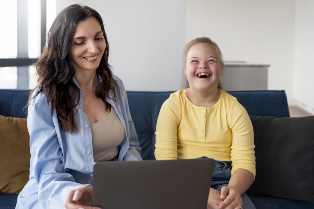 Fotografía de niña con sindrome down utilizando una computadora junto a su madre